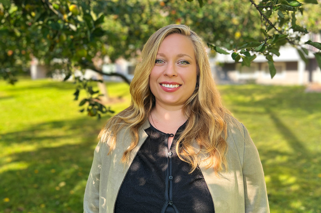 Sabine Olofsson, Samordnare på Solberga by, står bland äppelträden.