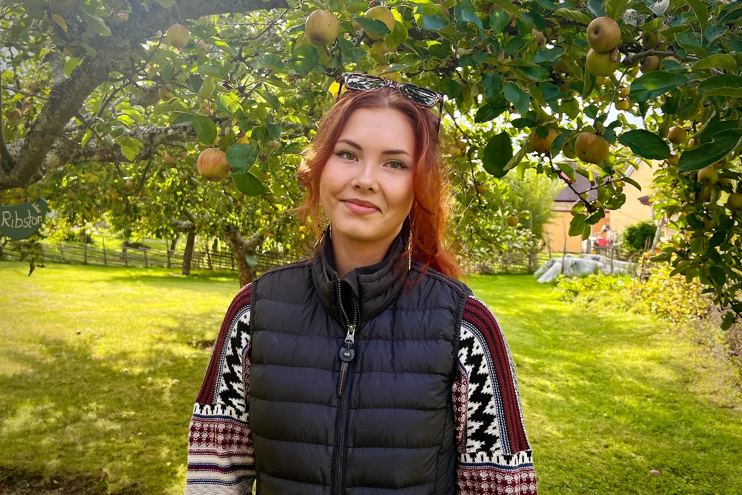 Tuva Widmark, Boendestödjare på Solberga by, står under ett äppelträd en solig höstdag.